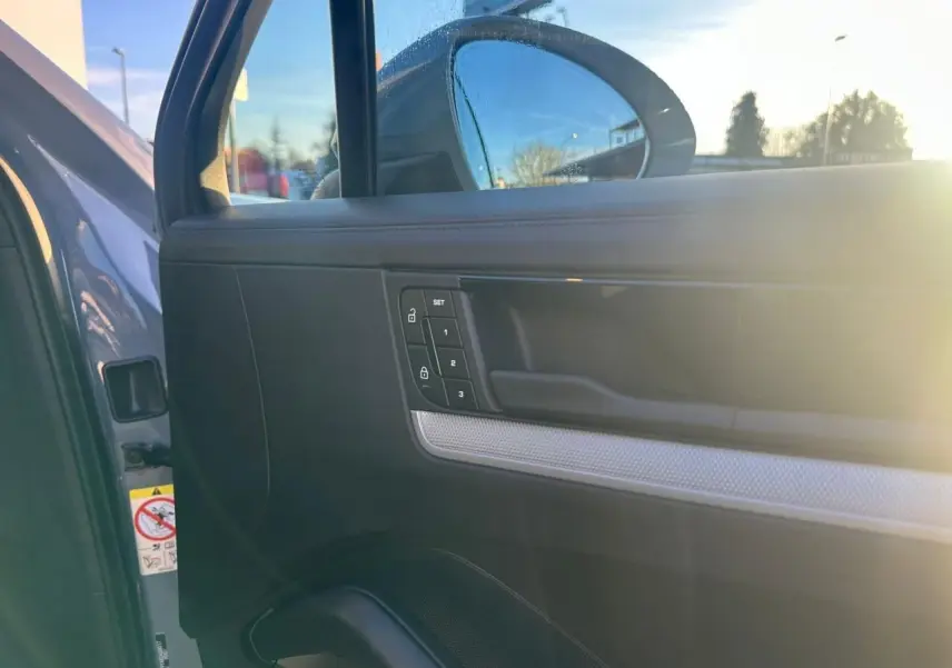 Détail de la porte avant gauche du Porsche Cayenne 2024 gris arctique, avec commandes de verrouillage et miroir extérieur.