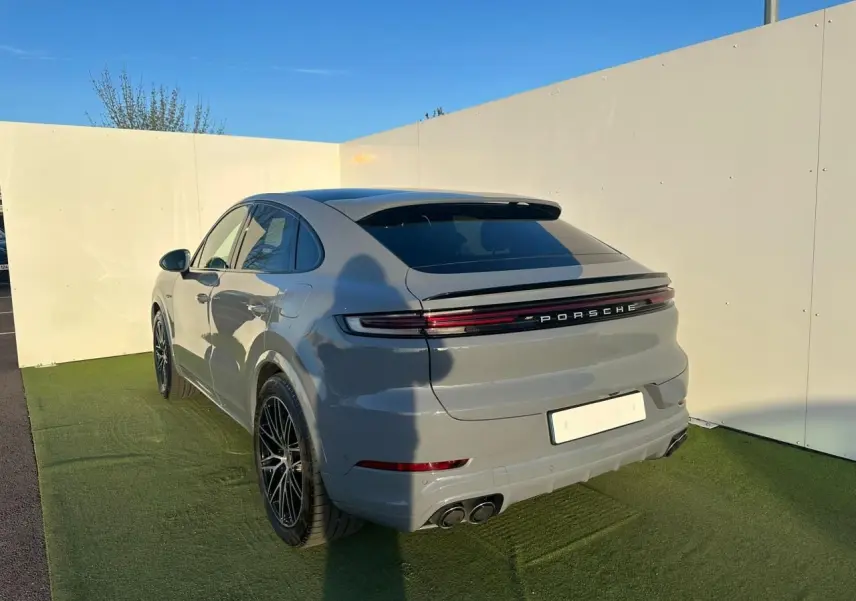 Vue 3/4 arrière droite d'un Porsche Cayenne Coupé 2024 gris arctique avec feux arrière continus et double sortie d'échappement.