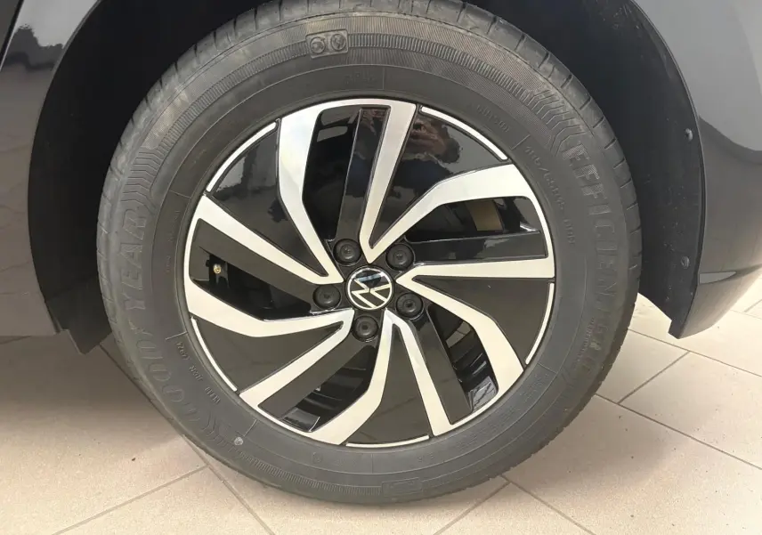 Gros plan sur la jante alliage 15'' bicolore noir et argent avec logo Volkswagen sur une Polo noir intense.