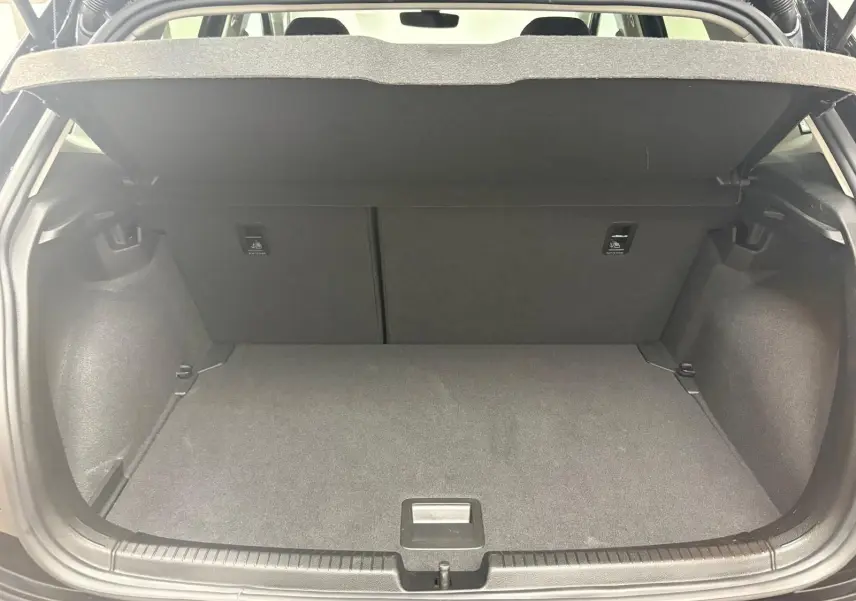 Coffre ouvert de Volkswagen Polo noir intense 2025, vue arrière montrant l'espace de chargement vide et la tablette cache-bagages.