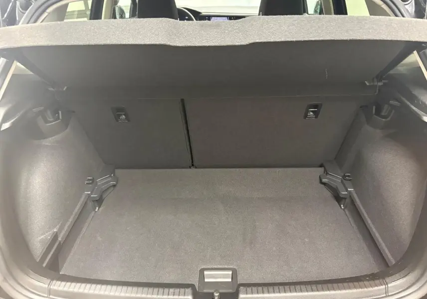 Coffre ouvert de Volkswagen Polo noir intense 2025, vue intérieure montrant l'espace de chargement vide et tapis gris.