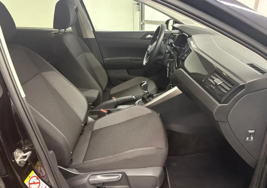 Intérieur avant de la Volkswagen Polo noir intense, vue côté conducteur montrant sièges et tableau de bord moderne.