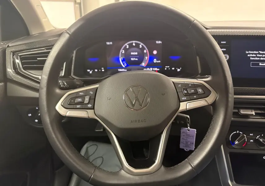 Vue rapprochée du volant cuir multifonctions noir de la Volkswagen Polo 2025 avec tableau de bord digital et écran tactile.