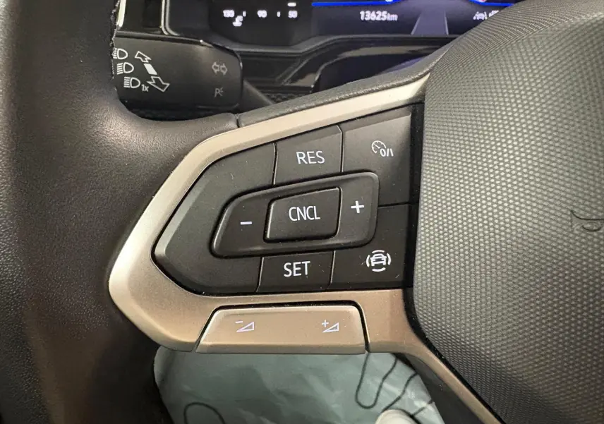 Gros plan sur les commandes du volant cuir de la Volkswagen Polo 2025, boutons de régulateur de vitesse visibles.