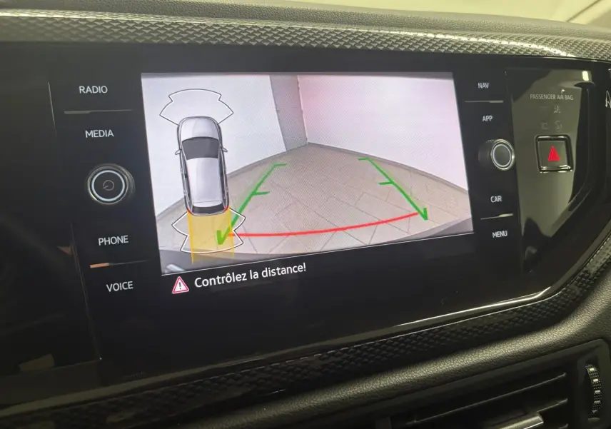 Écran tactile intérieur affichant la caméra de recul avec vue aérienne du véhicule gris et lignes de guidage colorées.