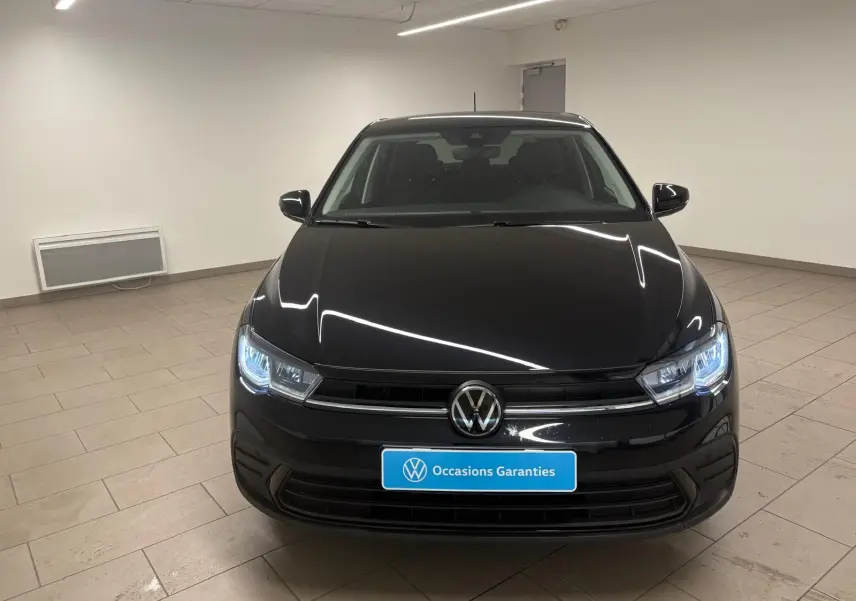 Vue frontale d'une Volkswagen Polo noire intense avec phares LED allumés dans un showroom.