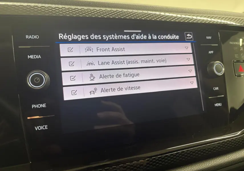 Écran tactile intérieur affichant les réglages d'aide à la conduite dans une Volkswagen Polo noire.
