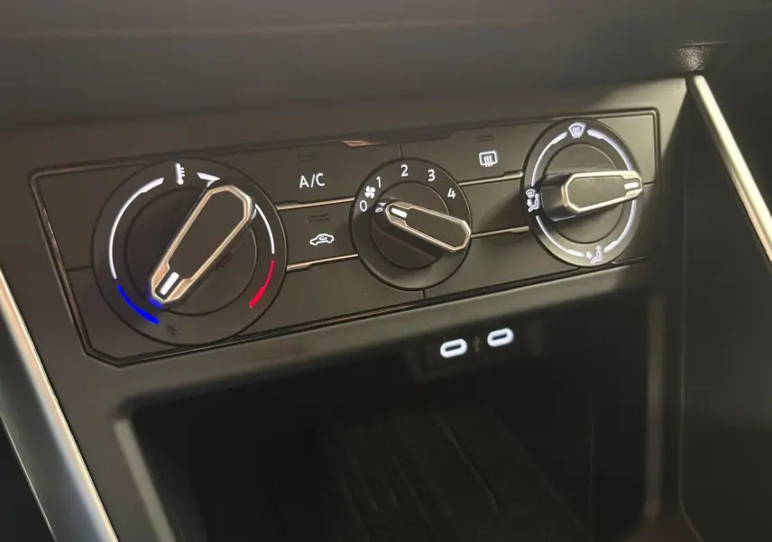 Gros plan sur les commandes de climatisation manuelle noire avec trois molettes dans une Volkswagen Polo 2025.