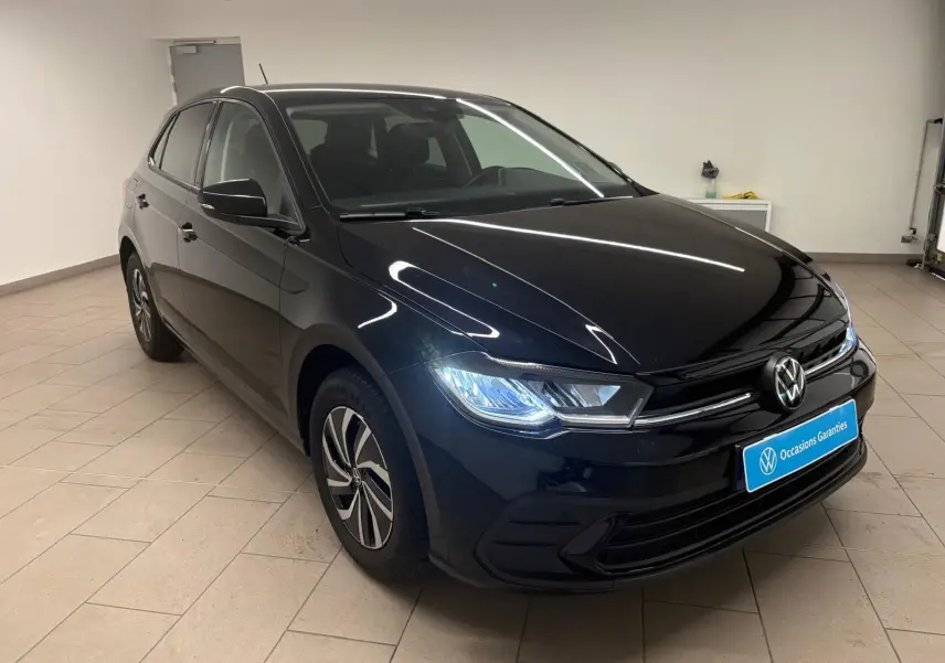 Volkswagen Polo noir intense vue 3/4 avant droit avec phares LED allumés en intérieur showroom.