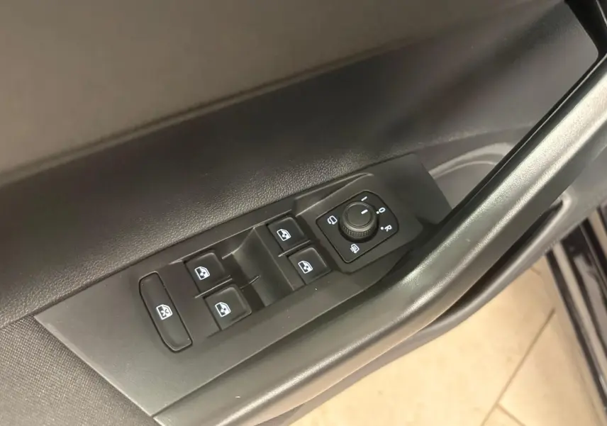 Vue rapprochée des commandes de lève-vitres et réglage des rétroviseurs sur la porte côté conducteur d'une Volkswagen Polo noire.