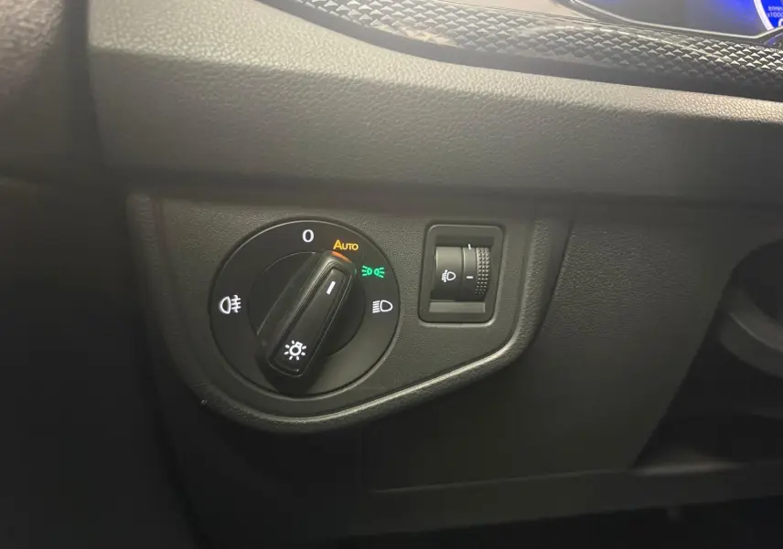 Gros plan sur le bouton d'allumage automatique des phares avec réglage d'intensité sur tableau de bord noir de Volkswagen Polo.