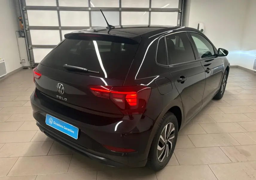 Vue 3/4 arrière droite d'une Volkswagen Polo noire intense avec feux arrière LED et jantes alliage 15 pouces dans un garage.