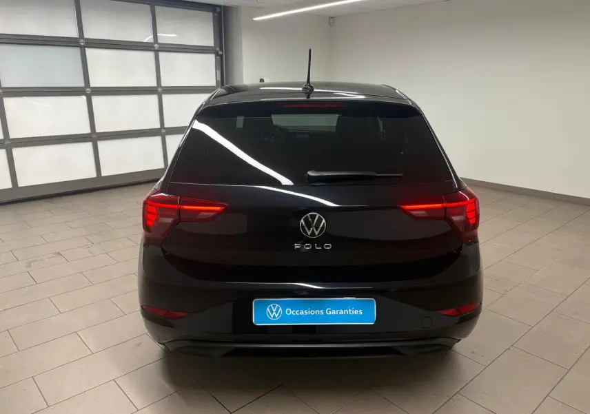 Vue arrière d'une Volkswagen Polo noire intense avec feux arrière LED allumés dans un garage lumineux.
