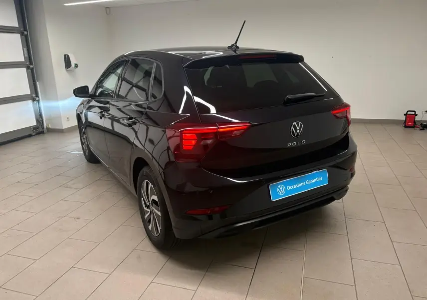 Vue 3/4 arrière droite d'une Volkswagen Polo noire intense avec feux arrière LED, jantes alliage et vitres surteintées.