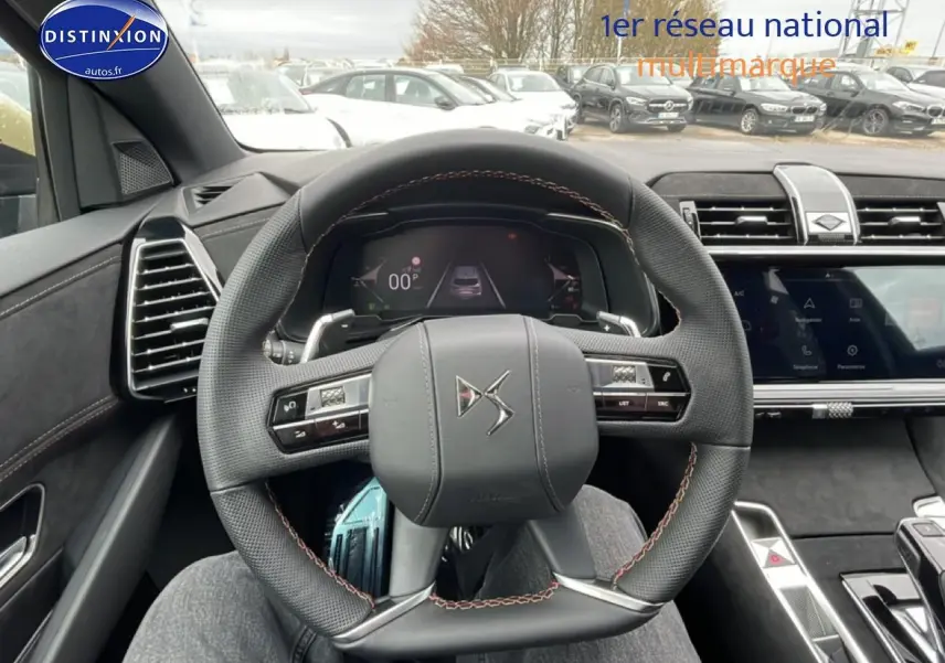 Vue intérieure centrée sur le volant cuir DS du DS7 2026, avec tableau de bord numérique et écran tactile visible.