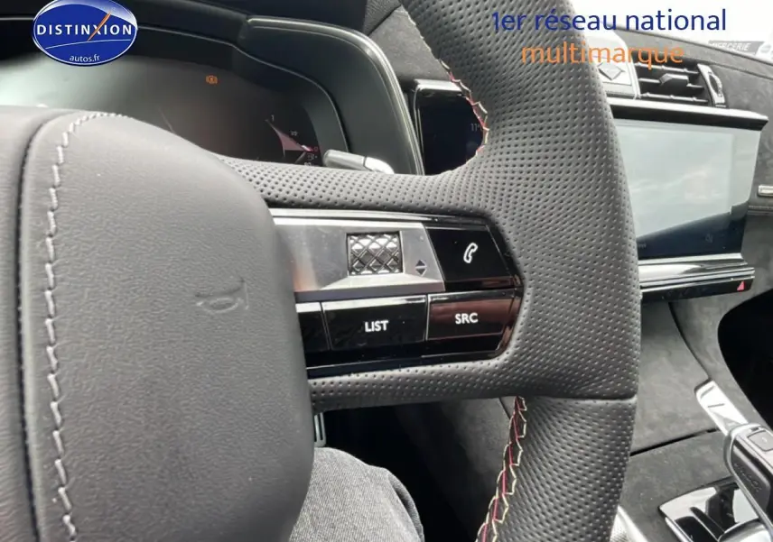 Vue intérieure centrée sur le volant cuir perforé avec commandes intégrées du DS7 gris titane 2026.