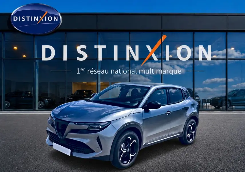 Alfa Romeo Junior 1.2 hybride gris en 3/4 avant droit, avec jantes alliage et vitres arrière teintées, devant showroom Distinxion.