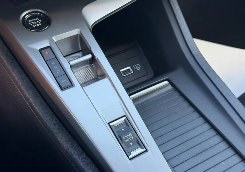 Gros plan sur la console centrale argentée de la Peugeot 308 Hybrid avec levier de boîte auto et bouton Drive Mode.