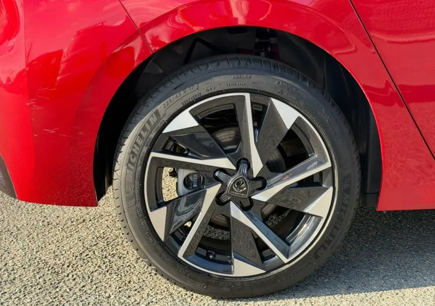 Gros plan sur la jante alu noire et argentée de la roue arrière droite d'une Peugeot 308 rouge Elixir.