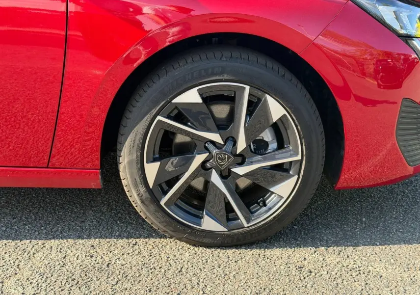 Gros plan sur la roue avant gauche de la Peugeot 308 rouge Elixir avec jante alliage au design moderne.