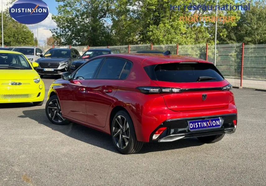 Vue 3/4 arrière droite d'une Peugeot 308 rouge Elixir avec jantes alliage et vitres arrière surteintées.