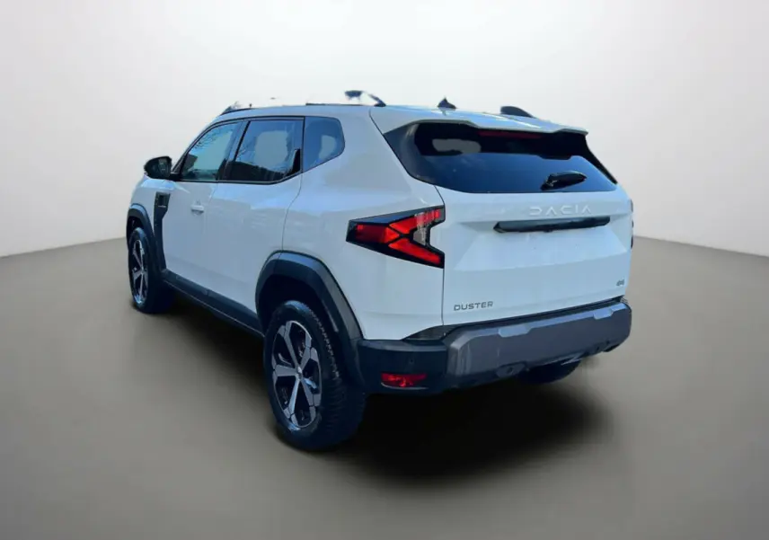 Vue 3/4 arrière du Dacia Duster blanc glacier 2025 avec jantes alliage et feux arrière en forme de flèche.