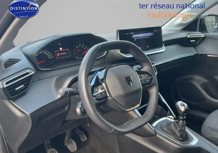 Vue intérieure côté conducteur du tableau de bord et volant de la Peugeot 208 gris Artense avec boîte manuelle.