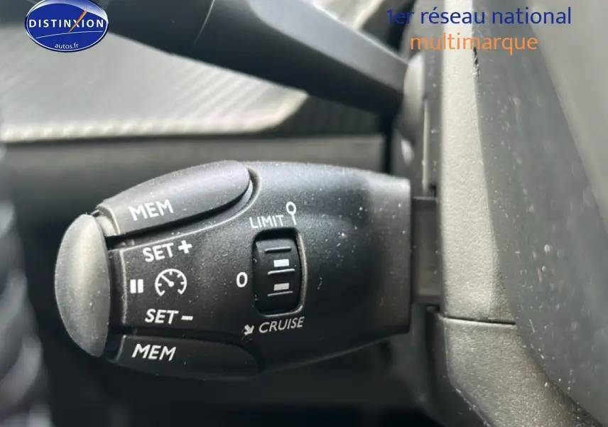 Gros plan sur la commande de régulateur de vitesse du Peugeot 208 1.2 100 style gris Artense, intérieur noir.