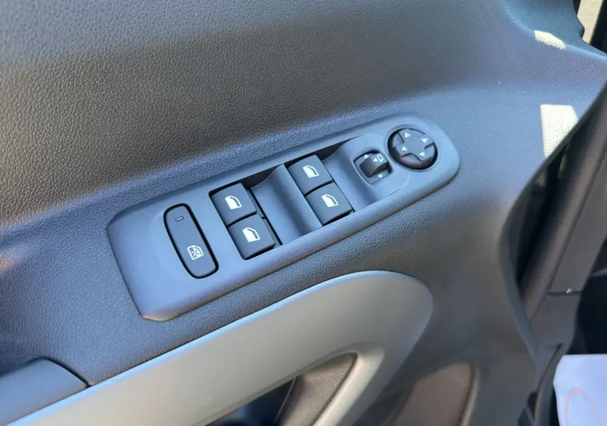 Gros plan sur les commandes des vitres électriques et rétroviseurs côté conducteur du Citroën Berlingo noir 2025.