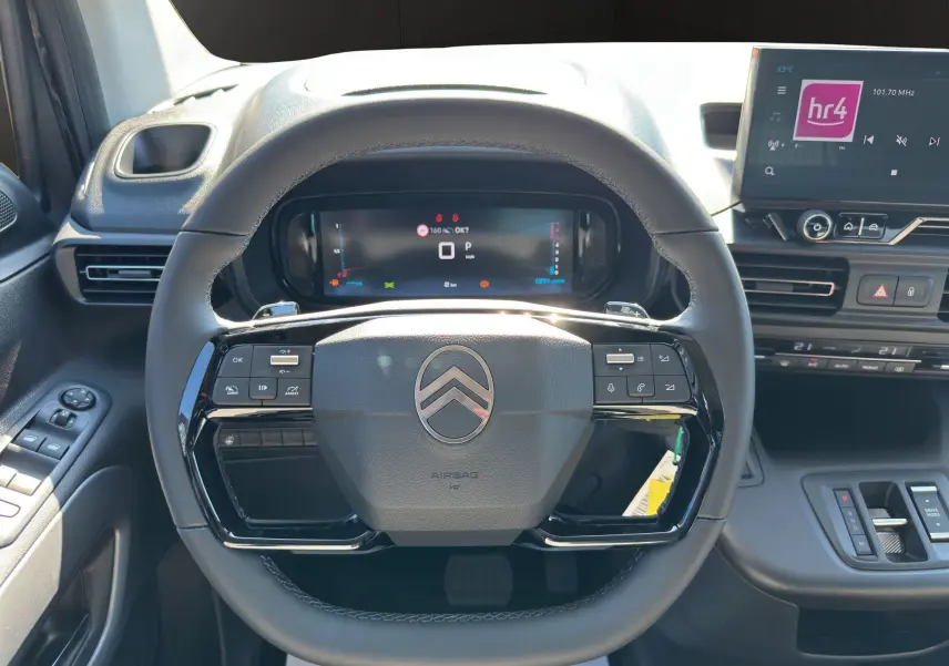 Vue intérieure centrée sur le volant noir du Citroën Berlingo 2025 avec tableau de bord numérique et écran tactile.