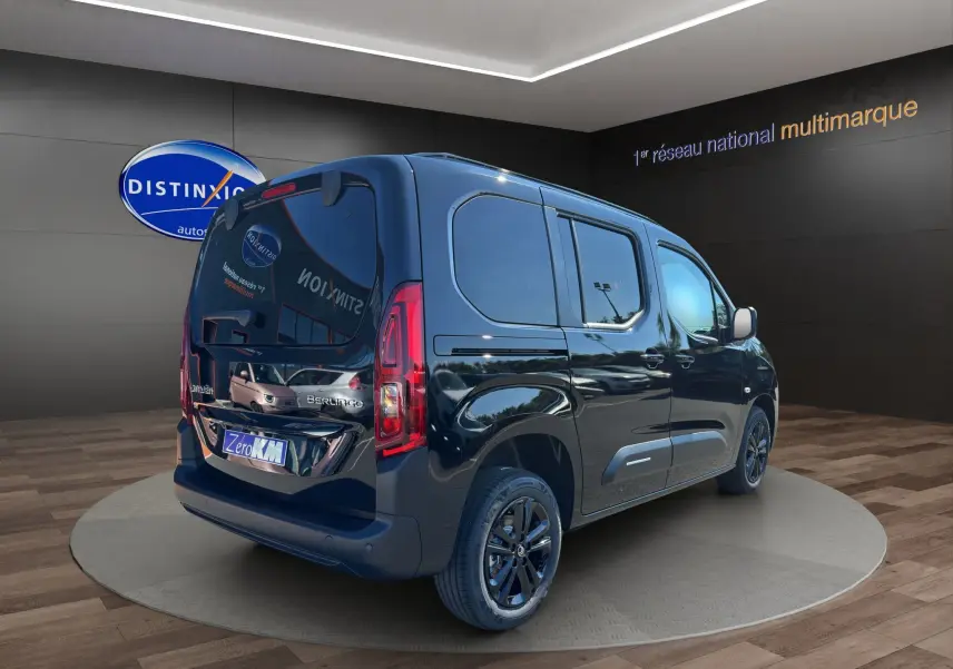 Vue 3/4 arrière droite d'un Citroën Berlingo noir avec vitres teintées et jantes alliage 16 pouces dans un showroom.