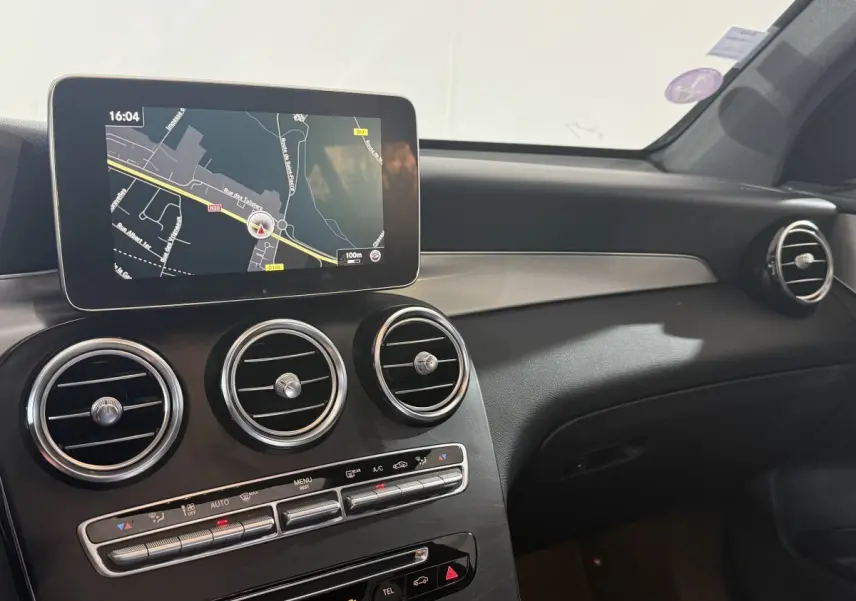Vue intérieure du tableau de bord du Mercedes GLC 250 Fascination 2019 avec écran de navigation et aérateurs ronds chromés.