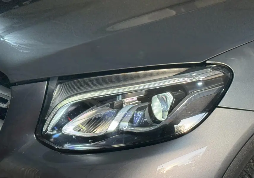 Gros plan sur le phare avant droit d’un Mercedes GLC 250 Fascination 4Matic gris foncé, montrant les détails LED.