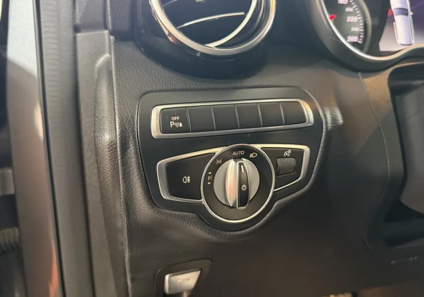 Détail du tableau de bord noir du Mercedes GLC 250 Fascination 2019 montrant la commande des phares et l'activation du stationnement.