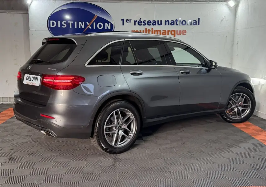 Mercedes GLC 250 Fascination gris foncé en 3/4 arrière droit, avec jantes alliage et feux arrière LED allumés.