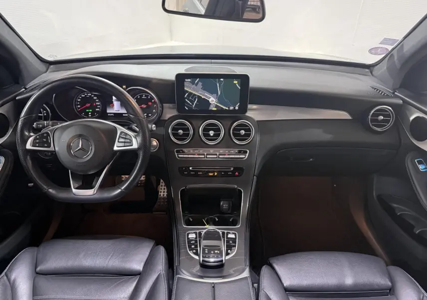 Vue intérieure avant du tableau de bord et volant cuir noir d'une Mercedes GLC 250 Fascination 2019 avec écran central de navigation.