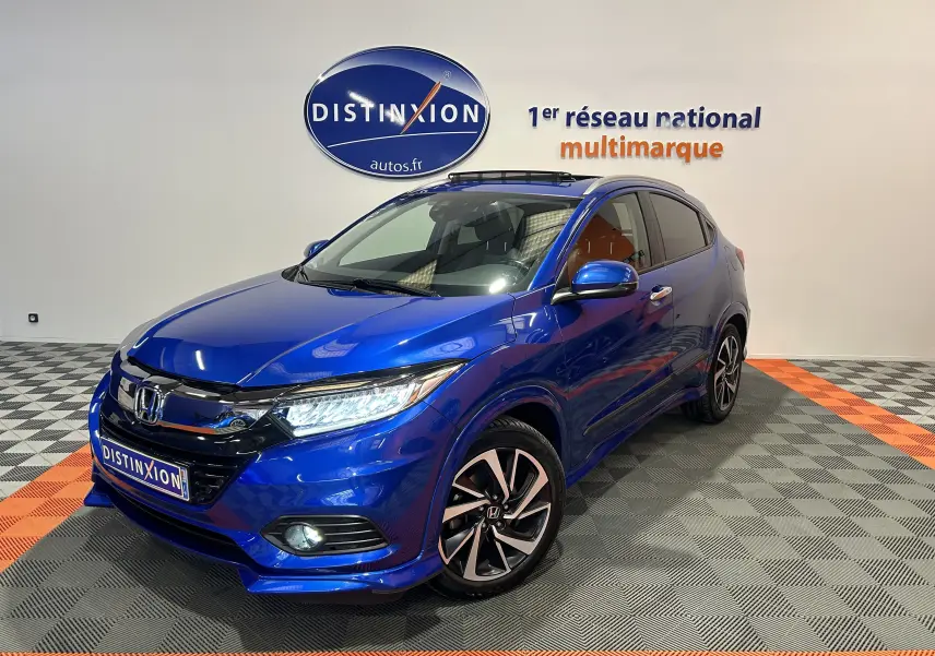 Vue 3/4 avant d'un Honda HR-V bleu avec toit ouvrant, jantes alliage et calandre noire brillante.