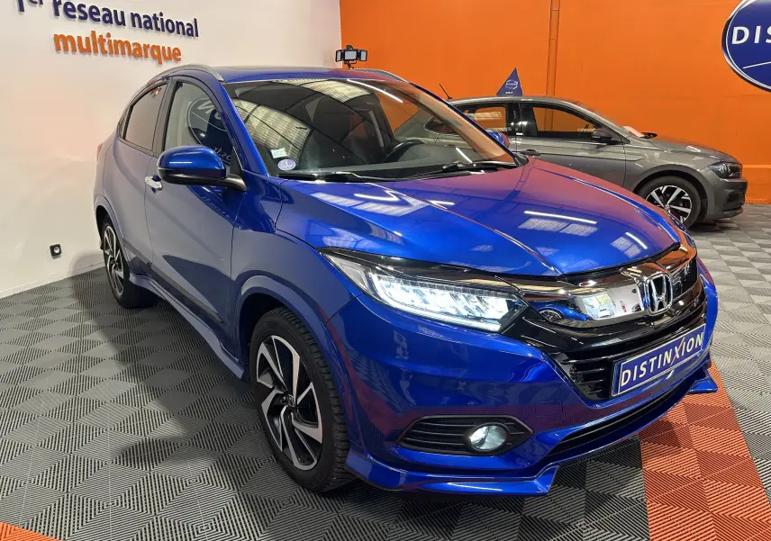 Vue 3/4 avant d'un Honda HR-V bleu avec jantes alliage et calandre chromée dans un showroom intérieur.