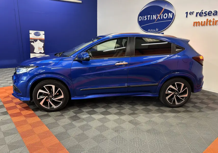 Vue de profil côté gauche d'un Honda HR-V bleu 2020 avec jantes bi-ton et vitres teintées dans un showroom.