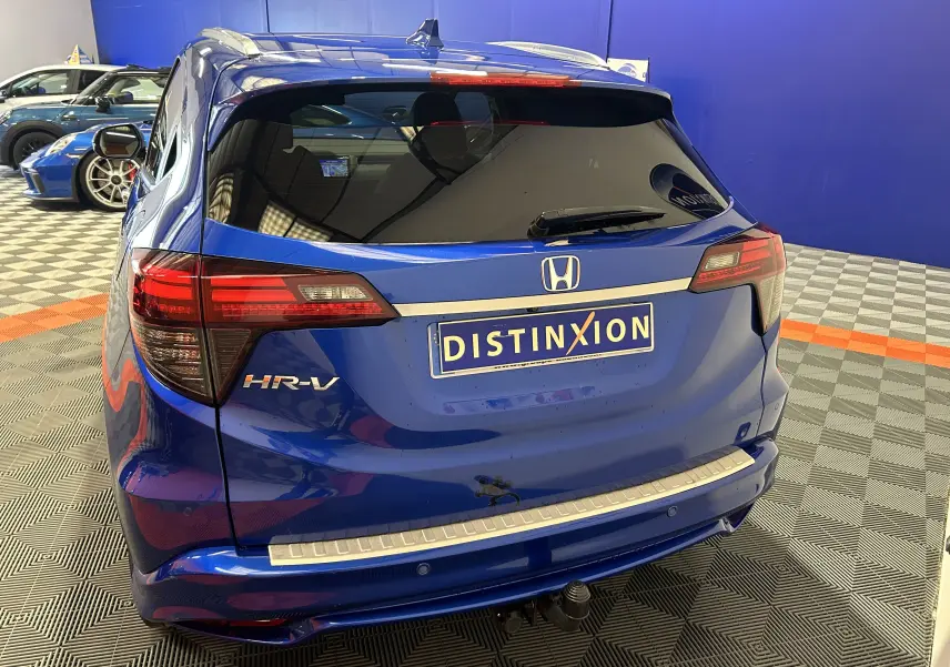 Vue arrière d'un Honda HR-V bleu 2020 avec toit ouvrant, attelage et vitres arrière teintées dans un showroom.