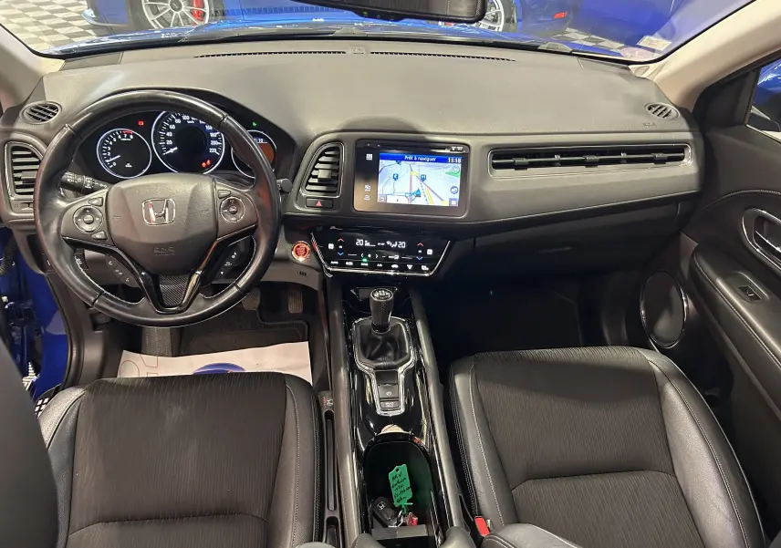 Vue intérieure avant du Honda HR-V bleu 2020, montrant le tableau de bord avec écran de navigation et volant cuir multifonction.