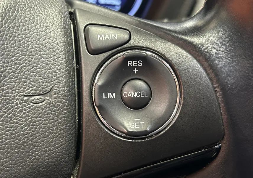 Gros plan sur les commandes de régulateur de vitesse au volant en cuir noir du Honda HR-V bleu 2020.