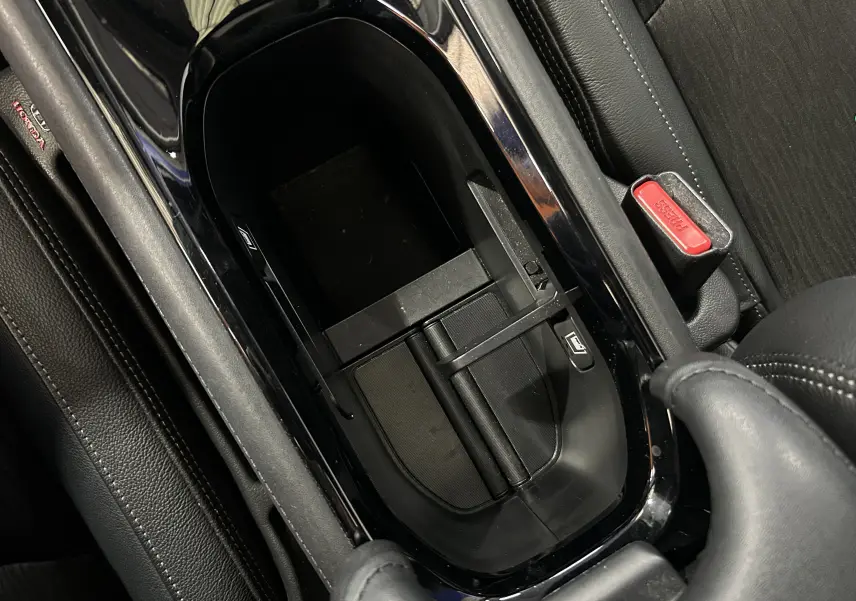 Vue rapprochée de la console centrale noire du Honda HR-V 2020, avec accoudoir et bouton de frein à main visible.