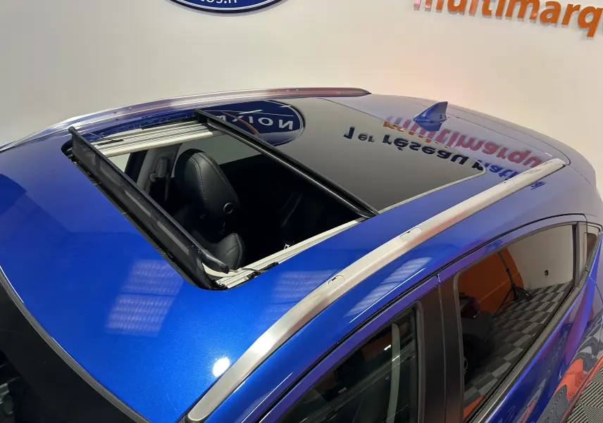 Vue plongeante sur le toit ouvrant ouvert d'un Honda HR-V bleu, mettant en valeur les barres de toit argentées.