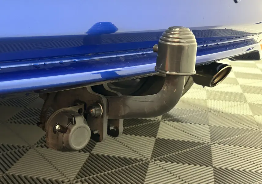 Gros plan sur l'attelage arrière d'un Honda HR-V bleu, avec prise électrique et sortie d'échappement visible en arrière-plan.