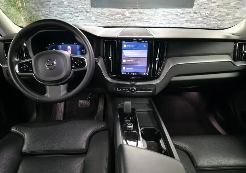 Intérieur noir du Volvo XC60 2023, vue frontale du tableau de bord avec écran tactile vertical et volant multifonction.