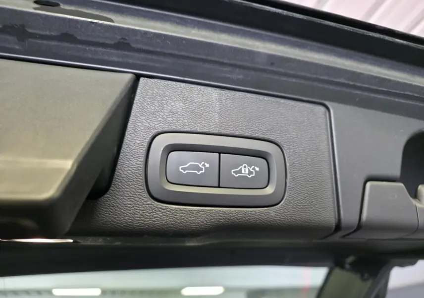 Gros plan sur les boutons d'ouverture et de verrouillage du hayon électrique du Volvo XC60 noir.