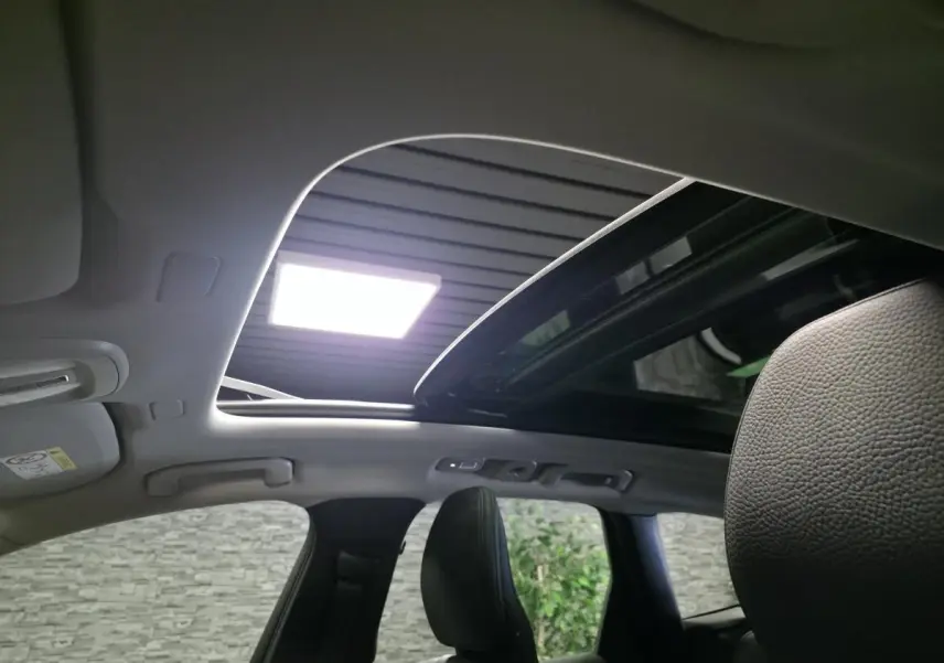 Toit ouvrant panoramique ouvert vu de l'intérieur arrière du Volvo XC60 noir, avec ciel de toit gris clair.