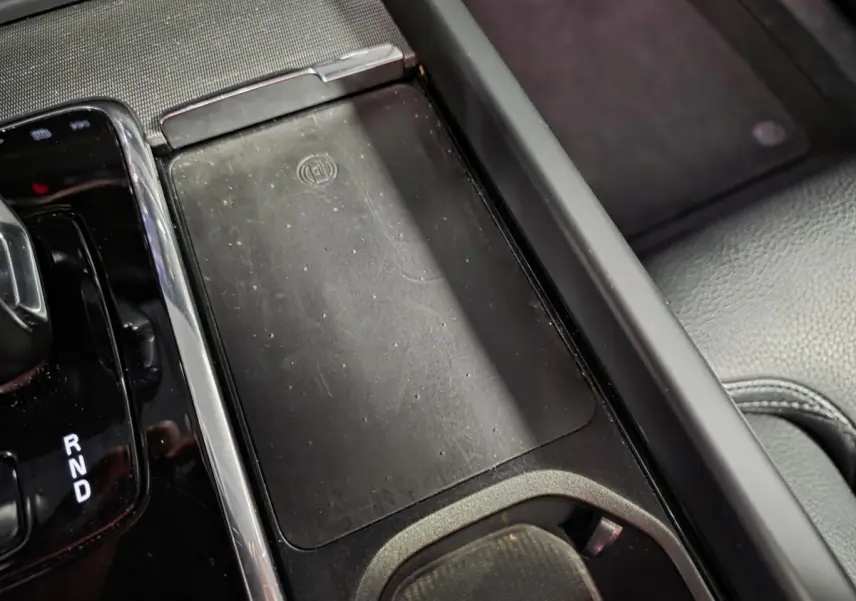 Détail de la console centrale noire du Volvo XC60 2023 avec chargeur sans fil et levier de vitesse automatique.