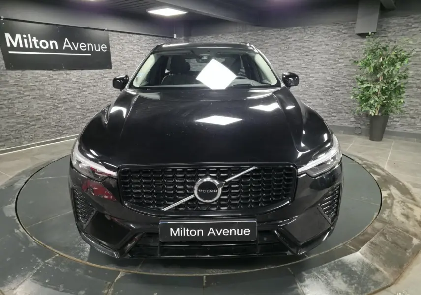 Vue de face du Volvo XC60 noir métallisé avec calandre et inserts noirs laqués dans un showroom.